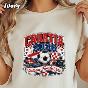 Croatia 2026 Vatreni Family Crew shirt with soccer ball, cleats, and score graphic.