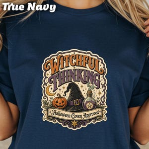 May include: True Navy t-shirt with a colorful graphic. The graphic features a witch's hat, a jack-o'-lantern, and a potion bottle, with the words "Witchful Thinking" and "Halloween Coven Approved".