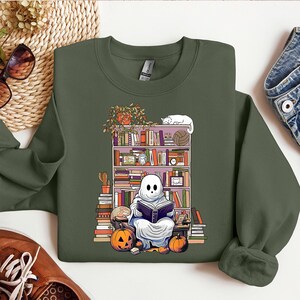 a green sweatshirt with a picture of a ghost reading a book