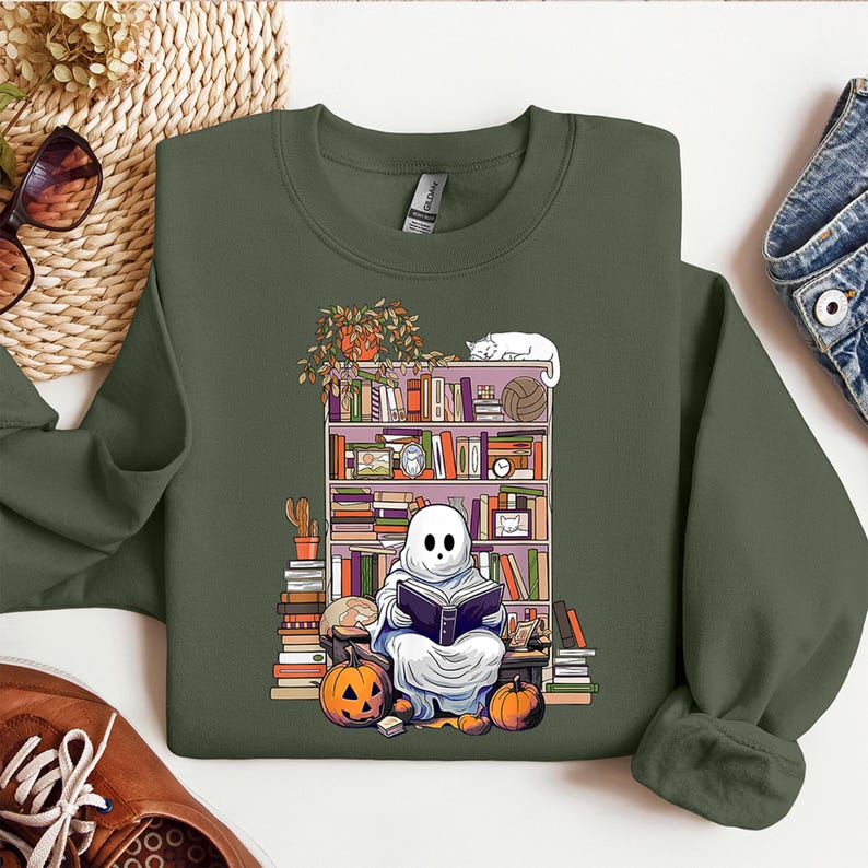 a green sweatshirt with a picture of a ghost reading a book