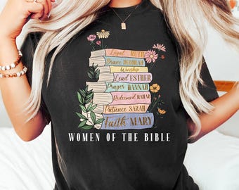 May include: Black t-shirt with a stack of colorful books featuring the names of women from the Bible. The text "Women of the Bible" is printed below the books.
