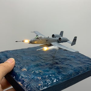 Modello di aereo d&#39;attacco Warthog A-10 Thunderbolt II in scala 1:144 con base oceanica e lancio di missili AGM-65 Maverick/AM-9 Sidewinder