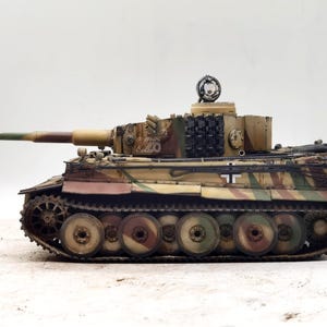 May include: A detailed model of a German Tiger I tank, painted in a camouflage pattern of brown, green, and tan. The tank has a black track and a white cross on the side. The tank is numbered "226".