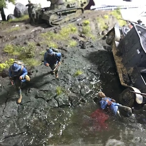 May include: A detailed diorama depicting a war scene with miniature soldiers in blue uniforms, a tank, and a vehicle overturned in a muddy environment. The scene includes water and vegetation, creating a realistic battlefield.