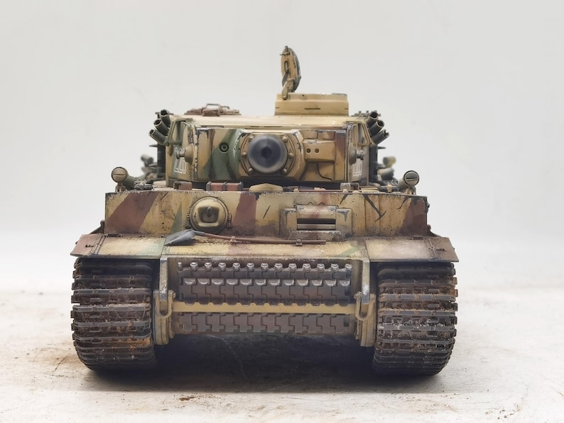 May include: A detailed model of a German Tiger I tank, painted in a camouflage pattern of green, brown, and tan. The tank has a large gun turret and tracks.