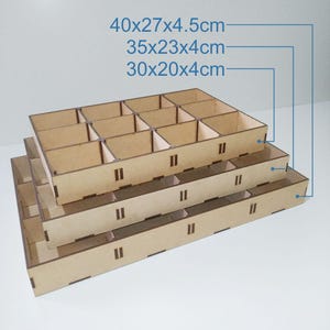 K&ouml;nnte beinhalten: Drei lasergeschnittene Holz-Aufbewahrungstabletts in verschiedenen Gr&ouml;&szlig;en, gestapelt. Das gr&ouml;&szlig;te Tablett misst 40x27x4.5cm, das mittlere 35x23x4cm und das kleinste 30x20x4cm. Text: "3 SIZES" und "LASER CUT FILE".