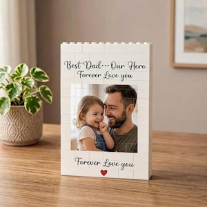 May include: A rectangular white building block frame featuring a printed photograph of a man and a young child. The text "Best Dad... Our Hero Forever Love you" is printed above the photo, and "Forever Love you" with a red heart below.