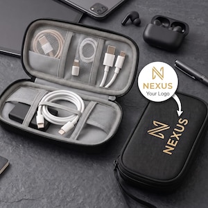 May include: A black rectangular zippered tech organizer case with a grey interior featuring mesh pockets and elastic straps holding white charging cables, a power adapter, and a small connector. The exterior features the gold text NEXUS.