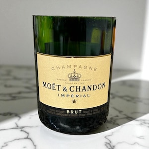 May include: A repurposed champagne glass made from a Moët & Chandon Imperial Brut bottle. The glass has a green tint and a gold label with black text. The label reads "CHAMPAGNE" and "MOËT & CHANDON IMPÉRIAL".