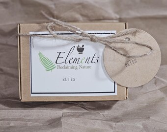 May include: A brown cardboard box with a white label that says "Elements Reclaiming Nature" and "Bliss". The box is tied with twine and has a brown paper circle tag that says "Bliss".
