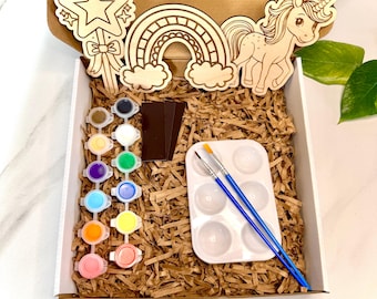 May include: A wooden craft kit featuring a unicorn, rainbow, and star. The kit includes paint, brushes, and a wooden palette.