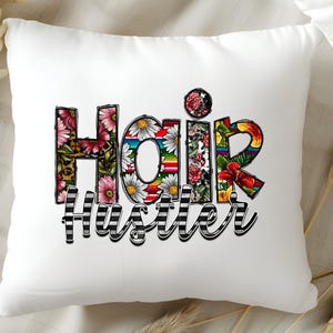 May include: White pillow with the words "Hair Hustler" in colorful letters with floral designs. The letters are outlined in black and white stripes.