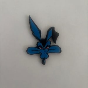 Puede incluir: Una cabeza de personaje de dibujos animados azul y negro con ojos rojos. El personaje tiene orejas largas y un hocico largo. La imagen es un primer plano de la cara del personaje, sobre un fondo blanco.