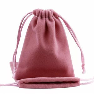 May include: A dusty rose drawstring pouch made of soft fabric. The pouch is closed with a drawstring and has a matching flat bottom pouch. The background is white.