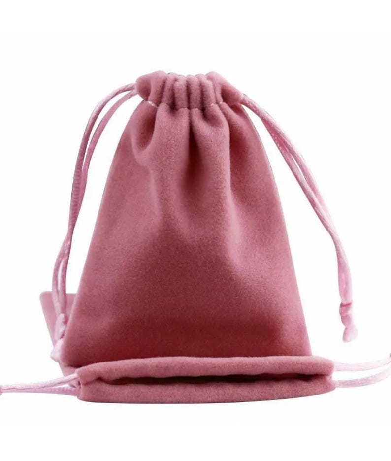 May include: A dusty rose drawstring pouch made of soft fabric. The pouch is closed with a drawstring and has a matching flat bottom pouch. The background is white.