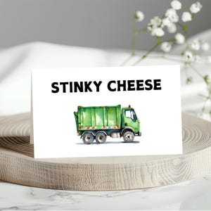 May include: A white card with the text "STINKY CHEESE" in black letters. A green garbage truck is illustrated on the card.