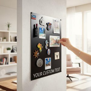 May include: A black magnetic board displaying souvenir magnets and photographs. The board features the text "YOUR CUSTOM TEXT". A hand is shown placing a photo. Magnets include a bottle, a thumbs-up, and a seahorse. The board is mounted on a white wall.