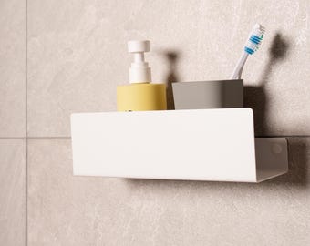 May include: A white, wall-mounted bathroom shelf holding a yellow soap dispenser, a gray cup with a toothbrush, and a gray cup. The shelf is rectangular with a small lip and a rounded corner.
