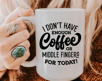 May include: White ceramic coffee mug with the text "I DON'T HAVE ENOUGH Coffee OR MIDDLE FINGERS FOR TODAY!" in black. The mug is held by a person wearing rings. The mug is a humorous gift.