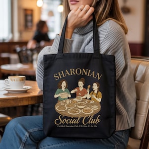Puede incluir: Bolso tote negro con el texto "SHARONIAN Social Club" y una ilustración de tres mujeres en una mesa con comida. El texto "Certified Sharonian Club: If It's Free, It's For Me" está debajo.