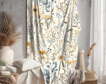 May include: A white throw blanket with a floral pattern featuring yellow, blue, and green flowers. The blanket is made of a soft, comfortable fabric and is perfect for adding a touch of nature to your home decor.