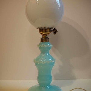 Pode incluir: Um abajur de mesa vintage com um globo de vidro branco e uma base de vidro azul claro com um design de espiral branco.