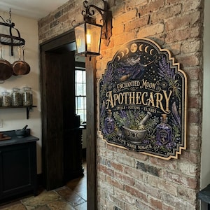 May include: A decorative wooden wall sign with a scalloped edge featuring the text Enchanted Moon Apothecary, Spells, Potions, Elixirs, and Let's Make Magick. The illustration includes a witch on a broom, moon phases, lavender, and bottles.