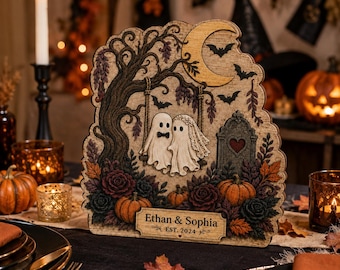 May include: A wooden decorative plaque featuring two ghosts on a swing under a crescent moon, surrounded by pumpkins, roses, and a tombstone. The text reads Ethan & Sophia EST. 2024. The design includes a tree, bats, and autumn leaves.