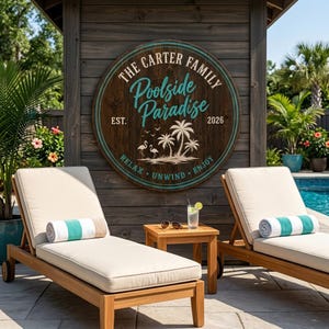 May include: A round wooden sign with a dark brown finish featuring the text THE CARTER FAMILY, Poolside Paradise, EST. 2026, and RELAX UNWIND ENJOY. The graphic includes white palm trees, two flamingos, and birds, all framed by a teal circular border.