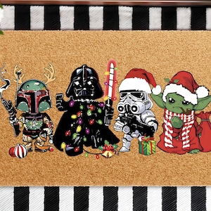 May include: A rectangular doormat with a brown surface features cartoon characters from Star Wars in festive attire. Boba Fett with antlers, Darth Vader with lights, a Stormtrooper with a Santa hat, and Yoda with a scarf and sack.