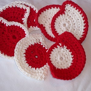 May include: Set of seven crocheted coasters in red and white. The coasters are round and have a white center with a red outer ring.