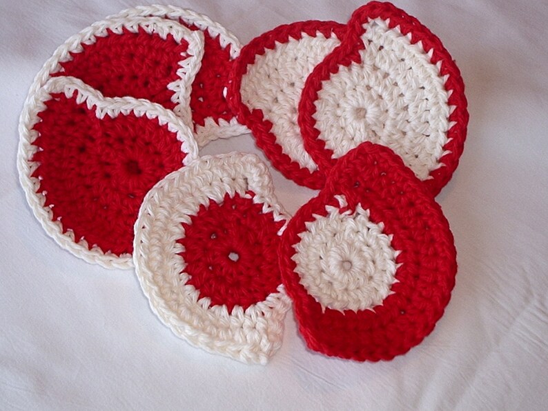 May include: Set of seven crocheted coasters in red and white. The coasters are round and have a white center with a red outer ring.