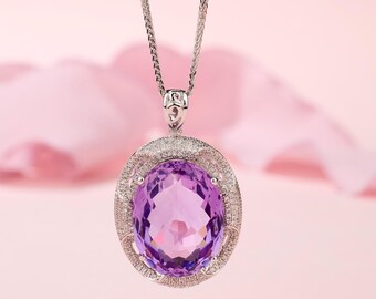 May include: A silver pendant necklace featuring a large, oval-cut amethyst gemstone. The amethyst is surrounded by a halo of small, sparkling stones. The necklace hangs from a delicate silver chain, creating an elegant and eye-catching piece of jewelry.