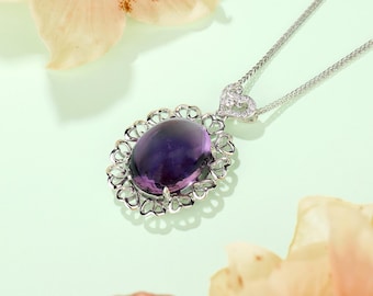 May include: A silver necklace with a heart-shaped pendant and a large oval amethyst gemstone surrounded by a delicate heart-shaped frame.