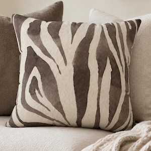 Cuscino quadrato in finta pelle scamosciata con stampa zebrata, decorazione moderna a tema animalier, elegante complemento d'arredo per il soggiorno.