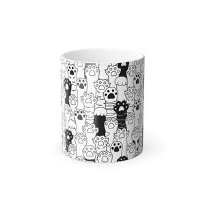 May include: White ceramic mug with a repeating pattern of black and white cat paws. The paw prints are stylized with varying designs, creating a playful and whimsical aesthetic. The mug has a standard cylindrical shape.