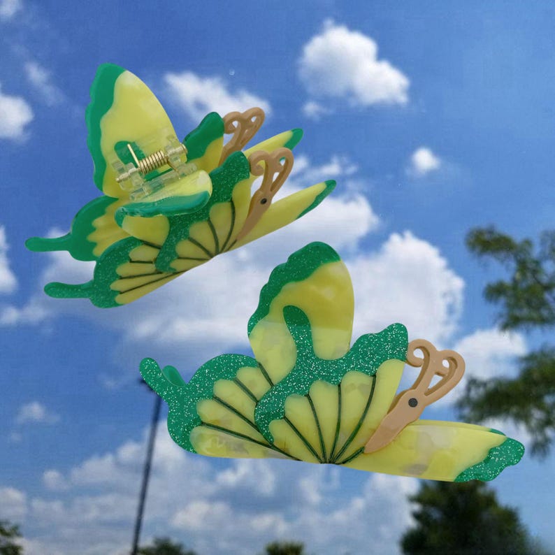 May include: Two yellow and green butterfly hair clips with glitter accents. The clips are made of plastic and have a spring-loaded mechanism.