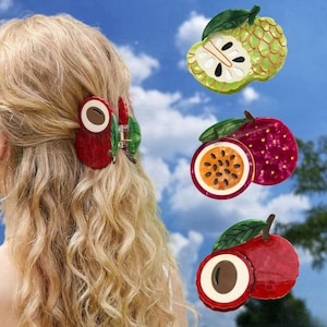 May include: A set of fruit-shaped hair claw clips featuring a red lychee design, a purple passion fruit design, and a green custard apple design. Each clip includes a green leaf accent and a realistic cross-section view of the fruit interior.