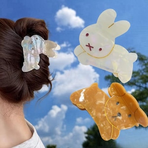May include: Three hair clips in the shape of animals. One is a white bunny, one is a brown bear, and one is a white bunny with iridescent details.