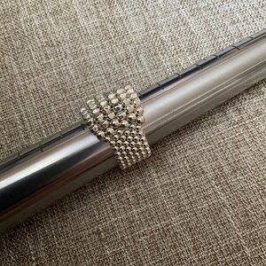 May include: A silver beaded ring with a textured surface. The ring is made of small, round beads that are tightly packed together.