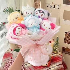 May include: A pink and white gingham bouquet with a pink ribbon and a variety of plush toys. The toys include a yellow and white bunny, a blue and white bear, a pink and white cat, a pink and white penguin, and a pink and white unicorn.