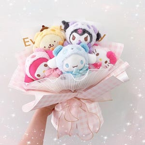 May include: A pink and white gingham bouquet of plush toys. The bouquet includes a yellow and brown dog, a purple and black cat, a blue and white bunny, and a pink and white cat.