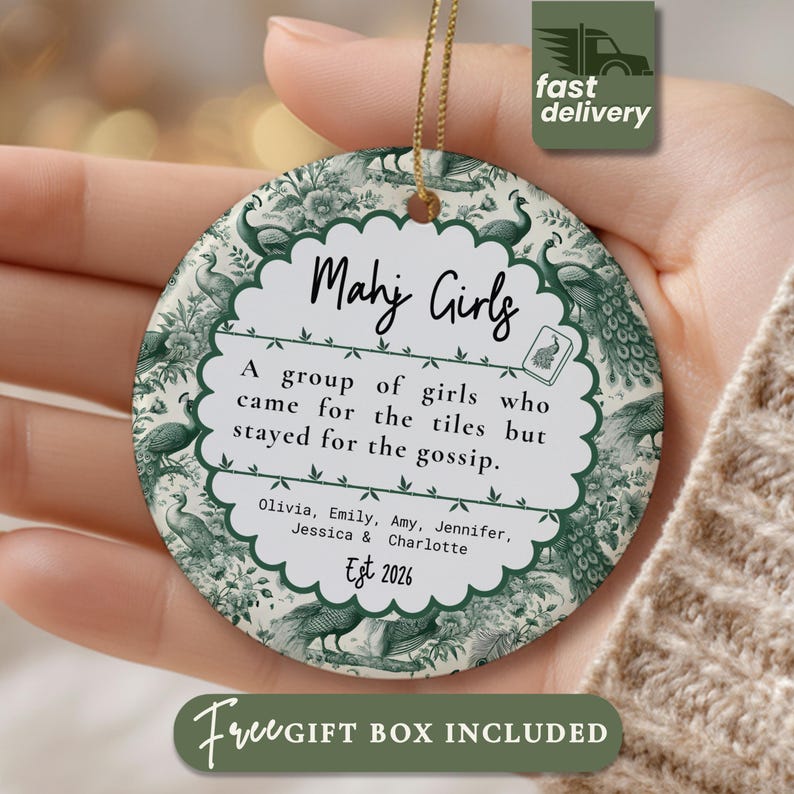 May include: A round ceramic ornament featuring a green and white toile pattern with peacocks. The center text reads: Mahj Girls, A group of girls who came for the tiles but stayed for the gossip, followed by the names Olivia, Emily, Amy, Jennifer, Jessica, Charlotte and Est 2026.