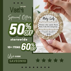May include: A round ceramic ornament with a gold string, featuring a beige floral pattern border and a white center. The text reads: Mahj Girls, Women who speak fluent Bam, Crak, Dot and gossip, Olivia, Emily, Amy, Jennifer, Jessica & Charlotte, Est 2026.