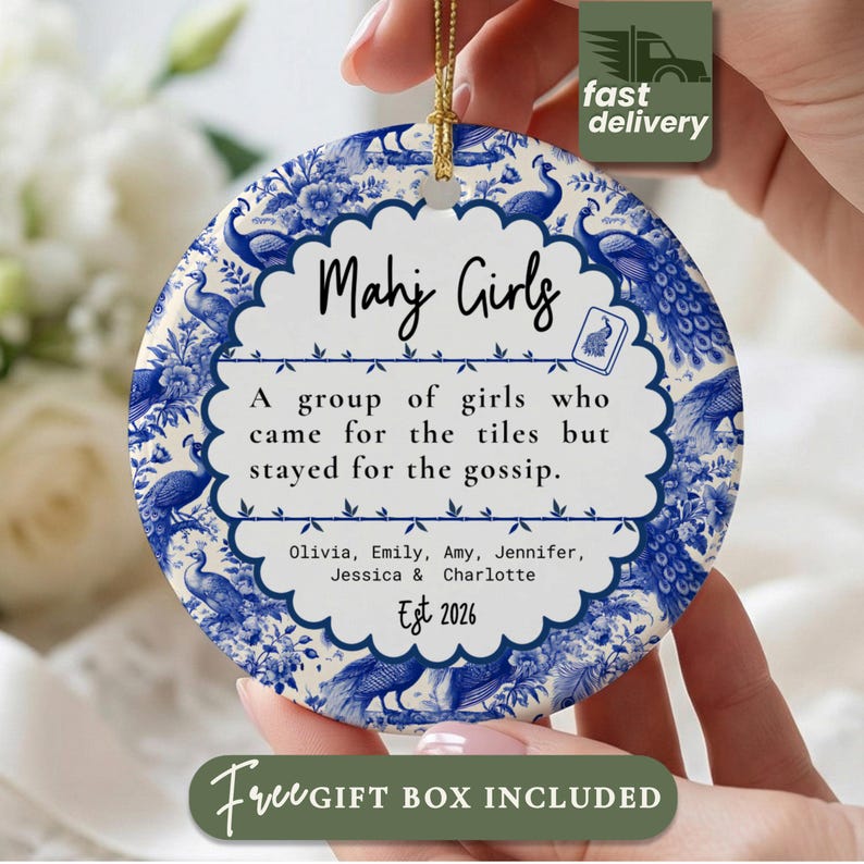 May include: A round ceramic ornament featuring a blue and white chinoiserie-style peacock pattern. The center has a scalloped white label with the text Mahj Girls, A group of girls who came for the tiles but stayed for the gossip, names, and Est 2026.