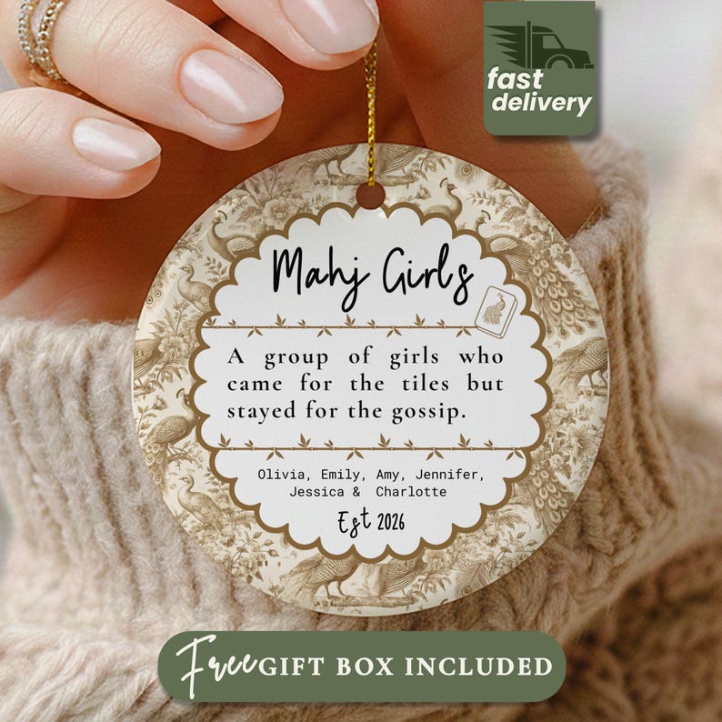 May include: A round ceramic ornament featuring a beige and white peacock pattern. The center has a scalloped white label with the text Mahj Girls, A group of girls who came for the tiles but stayed for the gossip, names, and Est 2026.