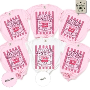 May include: Five short-sleeved t-shirts in blossom pink and white colors. Each shirt features a graphic of a mason jar filled with strawberries, with the text 'BERRY SWEET THIRD GRADE' and 'mrs. smith' printed on the jar, set against vertical stripes.