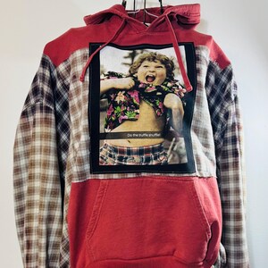 May include: Red hoodie with a plaid shirt sleeve and a graphic of a boy in a Hawaiian shirt with the text "Do the truffle shuffle!" printed on the front.