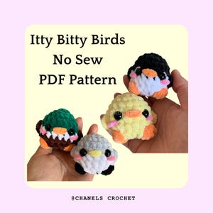 May include: A hand holds four small crocheted stuffed animals: a green duck, a yellow chick, a gray penguin, and a black and white penguin. The text "Itty Bitty Birds No Sew PDF Pattern" is at the top of the image. The text "@CHANELS CROCHET" is at the bottom of the image.