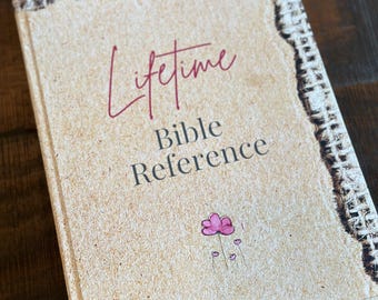 May include: A brown book with a burlap-like cover and the text "Lifetime Bible Reference" in white and red lettering. A small pink flower with a stem is drawn on the cover.